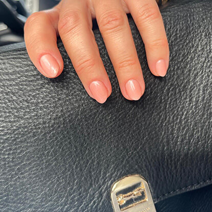 Photo of manicured nails holding a black leather bag